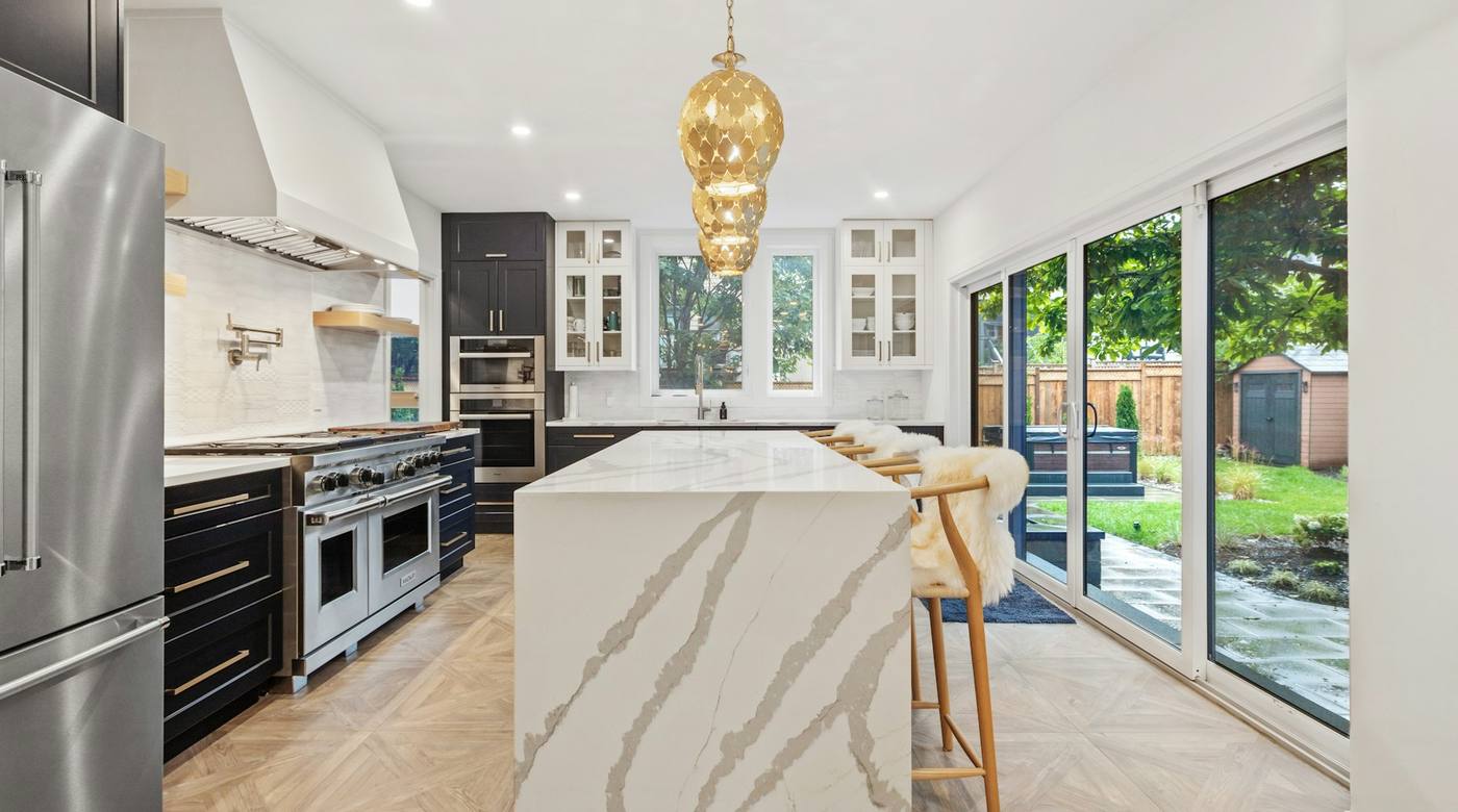 Luxury kitchen with a professional range beneath a custom hood and a marble island