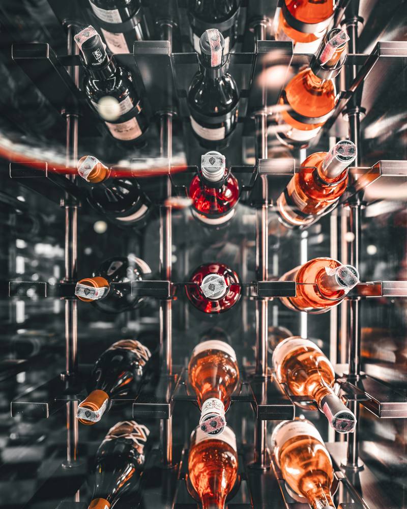 Bottles resting on shelves behind the glass door of a wine storage unit